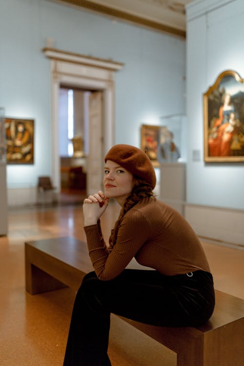 Free Portrait of a Young Brunette Wearing a Beret Sitting on a Bench Stock Photo