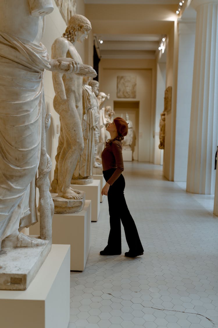 A Woman Looking At A Sculpture In A Museum