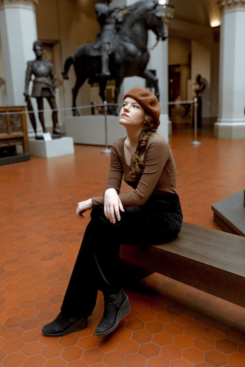 A Woman Sitting on a Bench Inside an Art Museum