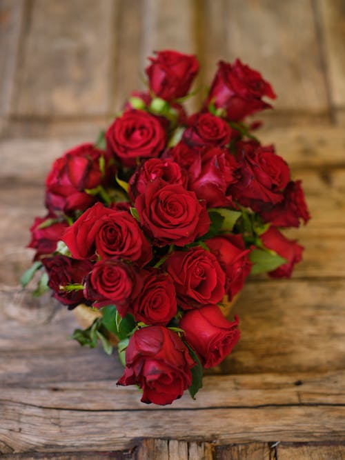 Close-Up Shot of Red Roses on Wooden Surface