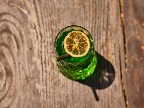 Free Top view of a green cocktail with a lemon slice on rustic wooden surface. Stock Photo