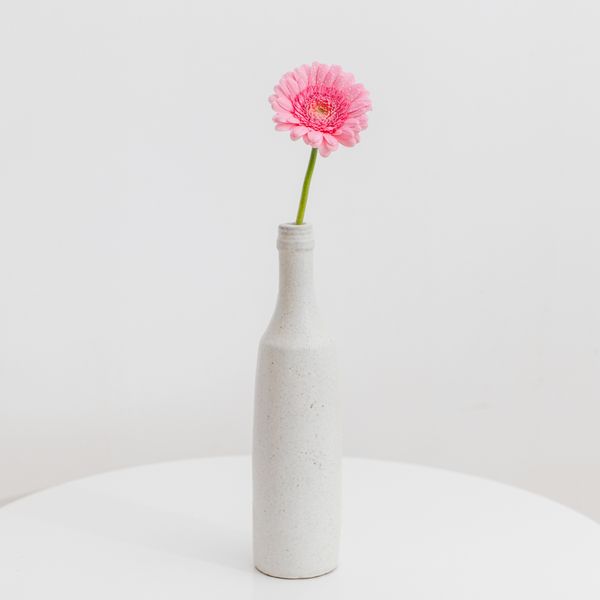 Speckled stoneware bud vase holding a single bloom — photo by Đặng Thanh Tú on Pexels