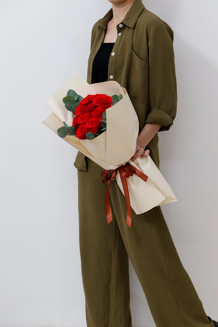 Woman Holding A Wrapped Bouquet Of Red Roses