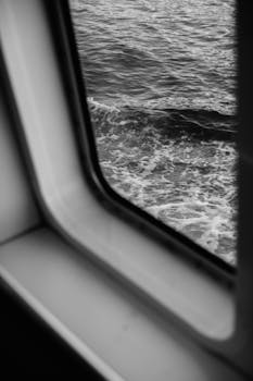 Monochrome view of ocean waves through a ship window, capturing the serene beauty of the sea.