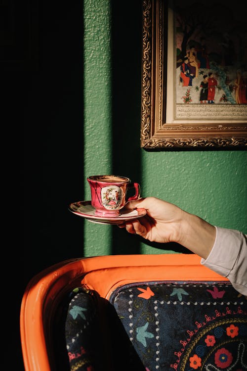 Free Shot of a Hand Holding a Porcelain Tea Cup in an Vintage Interior Stock Photo