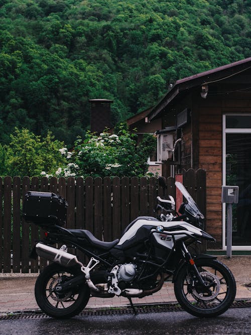Black and White Motorcycle Parked Beside Wooden House