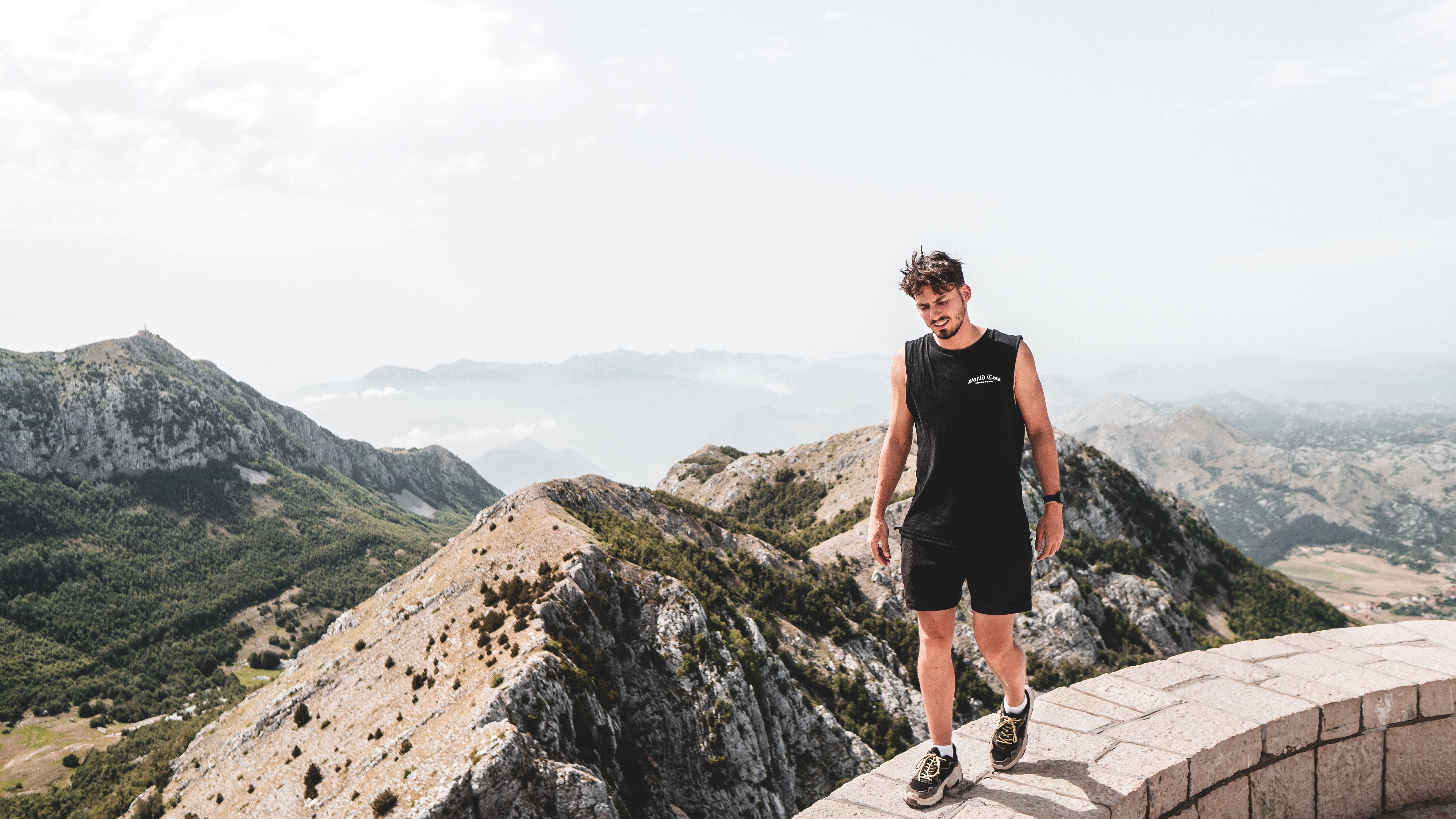 A man in black attire strolling along a mountain peak in Cetinje Municipality, Montenegro.