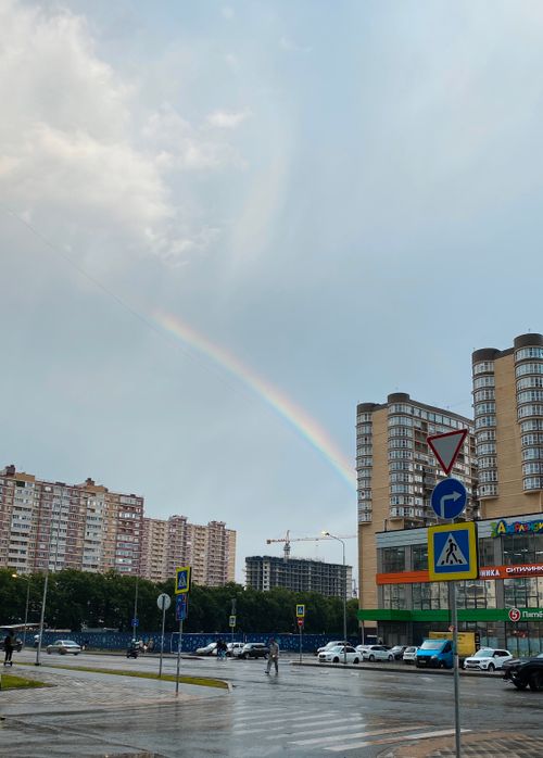 Free A vibrant rainbow arches over a city street, surrounded by buildings and traffic signs after a rain shower. Stock Photo