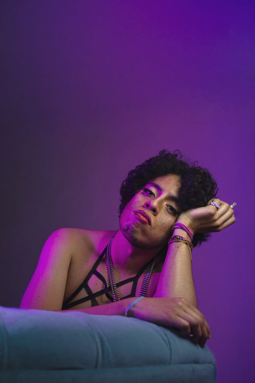 Free A creative portrait of a young man posing in vibrant purple lighting, exhibiting artistic expression. Stock Photo