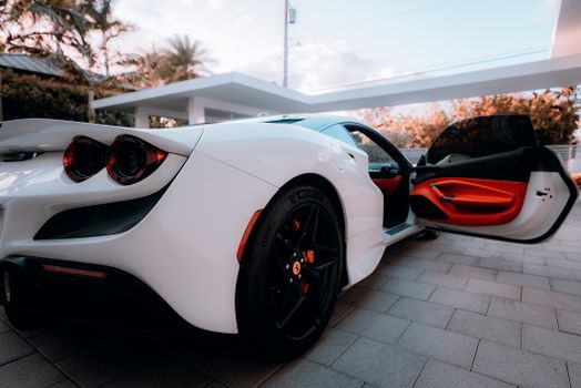 Luxurious white sports car with open door in an outdoor setting, showcasing modern design.