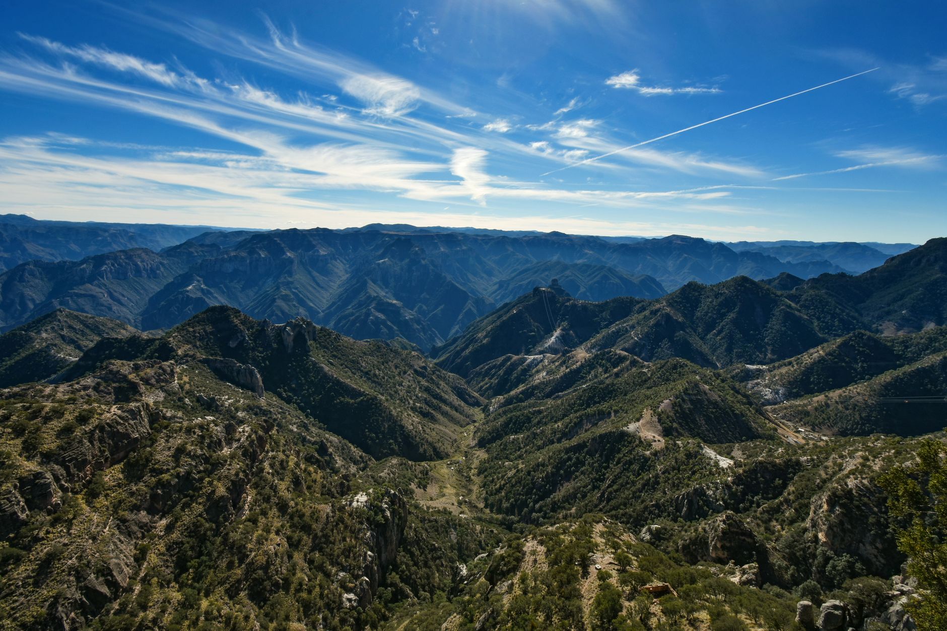 A breathtaking view of the Barrancas del Cobre mountain ranges under a vibrant blue sky.