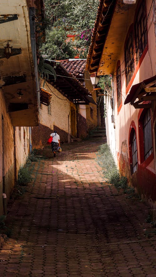 Person Walking on Narrow Street Between Houses