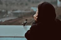 Woman in Black Hoodie Looking at the Window