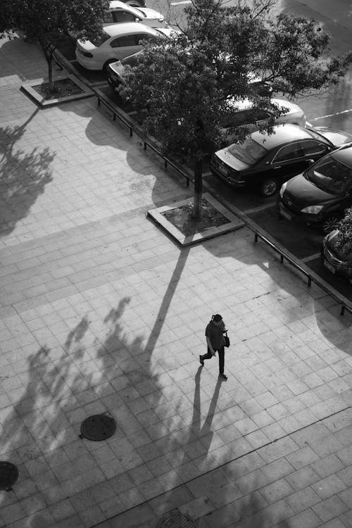 Grayscale Photo of Person Walking on Sidewalk