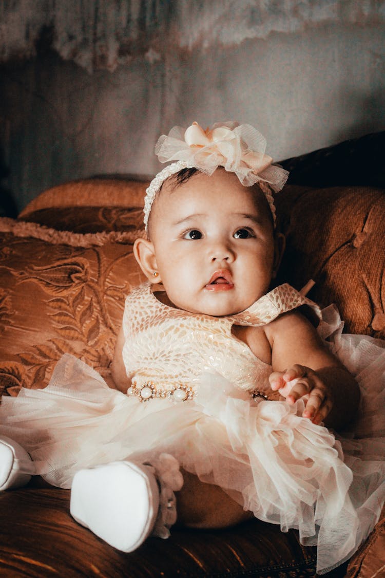 Baby In Dress With Headband Looking Up 