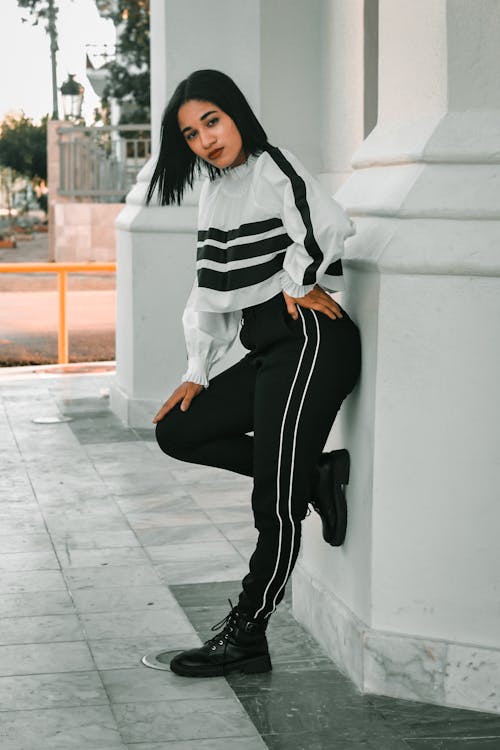 Free Woman in Black and White Stripe Long Sleeve Shirt and Black Pants Sitting on White Concrete Stock Photo