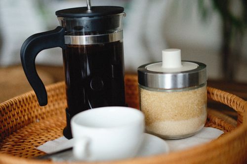 Free Close-up of a French press, sugar jar, and coffee cup on a wicker tray. Stock Photo