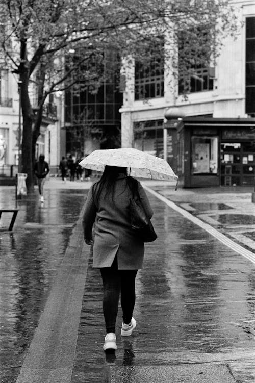 A Woman Walking with an Umbrella on a Rainy Day