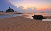 日出时分，海滩宁静，沙纹与岩石相映成趣