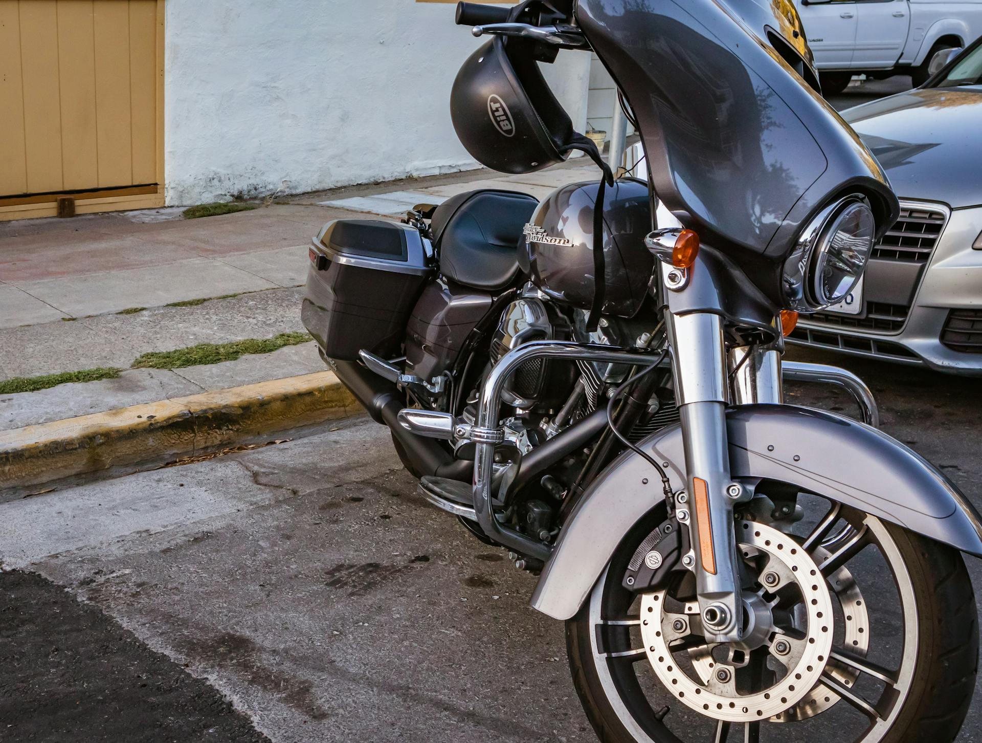 Close-up view of a cruiser motorcycle parked on a city street beside a sidewalk.