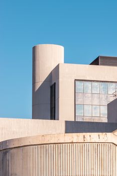 A modern building exterior with geometric lines under a clear blue sky.