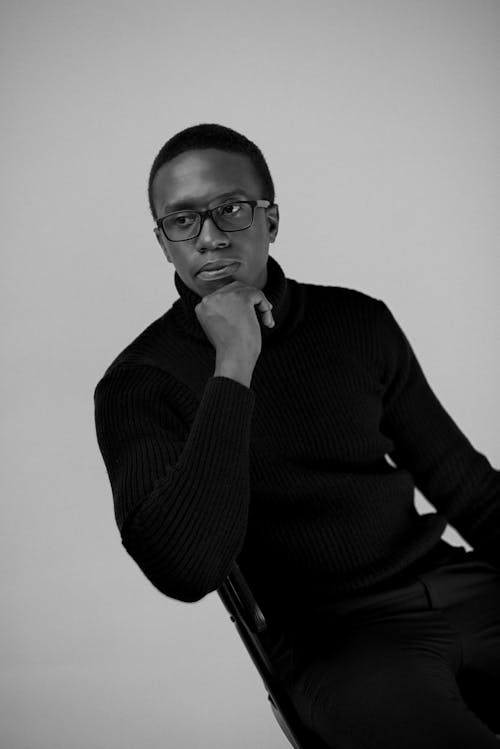 Grayscale Photo of Man Sitting on Chair