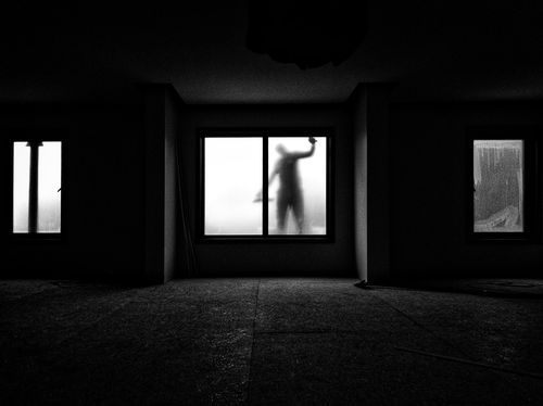Free Silhouette of a person cleaning windows viewed from inside a dimly lit room in İstanbul, Turkey. Stock Photo
