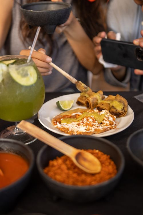 Free Close-up of a delicious Mexican meal with people capturing the moment in a vibrant setting. Stock Photo