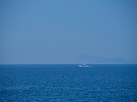 A tranquil ocean scene with a distant boat under a clear blue sky.