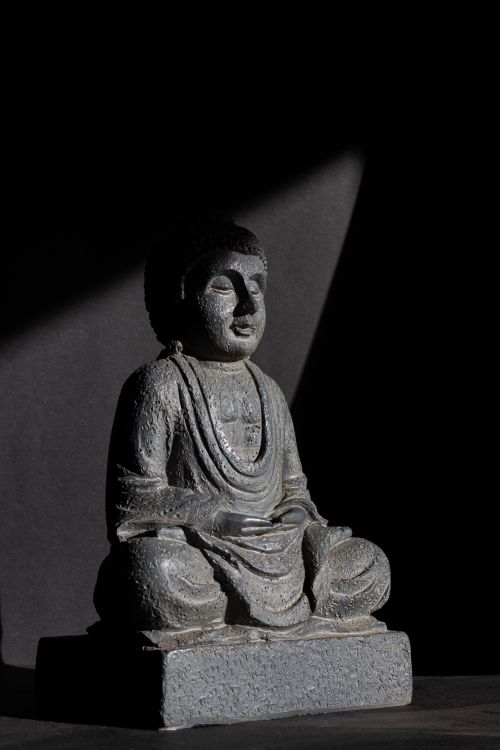 Free Sculpture of Buddha meditating in dramatic lighting, highlighting serenity and introspection. Stock Photo