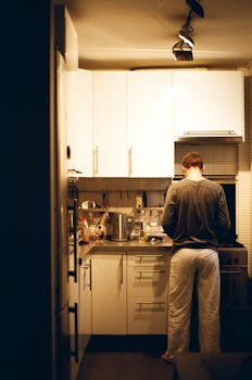A person cooking in a warm, cozy kitchen with soft ambient lighting.