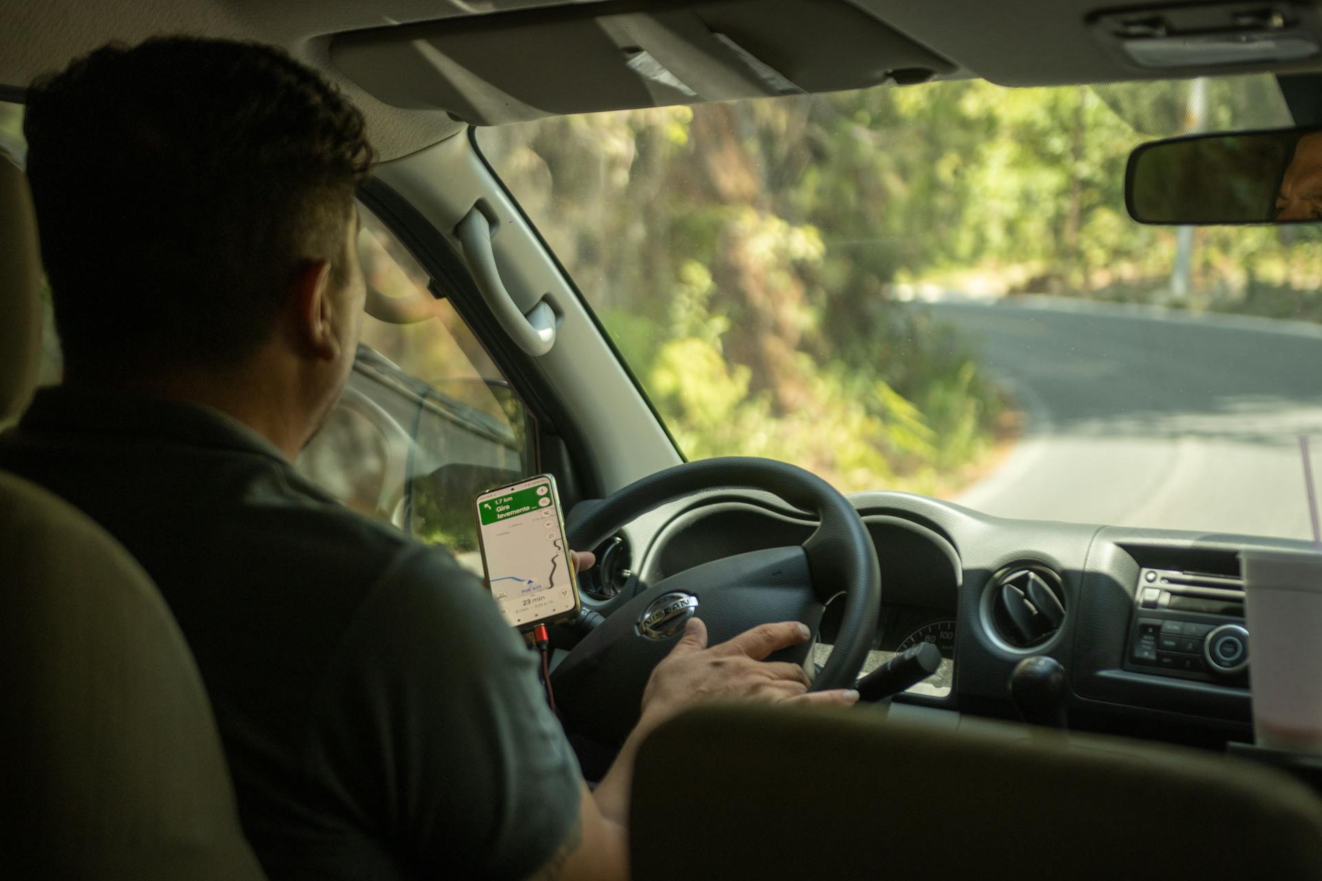 Man in Black Polo Shirt Driving Car Using a Mobile App for Navigational Aid