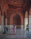 Woman in Pink Hijab Standing Near People Walking on Hallway