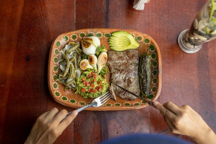 Photo Of Hand Cutting With A Fork And A Knife A Chop And A Plate With A Meal