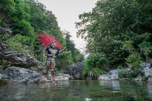 Man Standing in Tribal Wear Near Lake