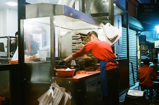 Street vendor preparing food at a night market, showcasing culinary skills in a lively stall.