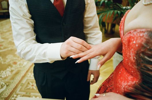Intimate close-up of a groom putting a ring on his bride's finger during a wedding ceremony.