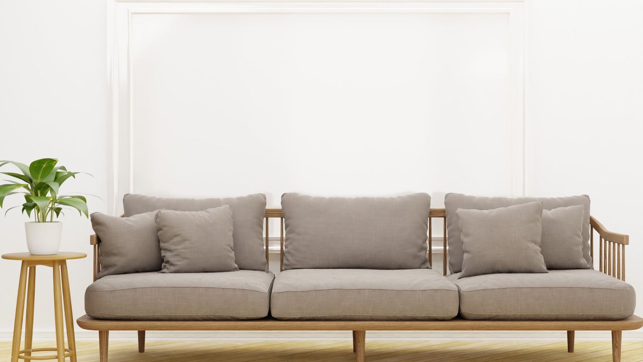 Mid-century wooden sofa with neutral matching cushions in a white room