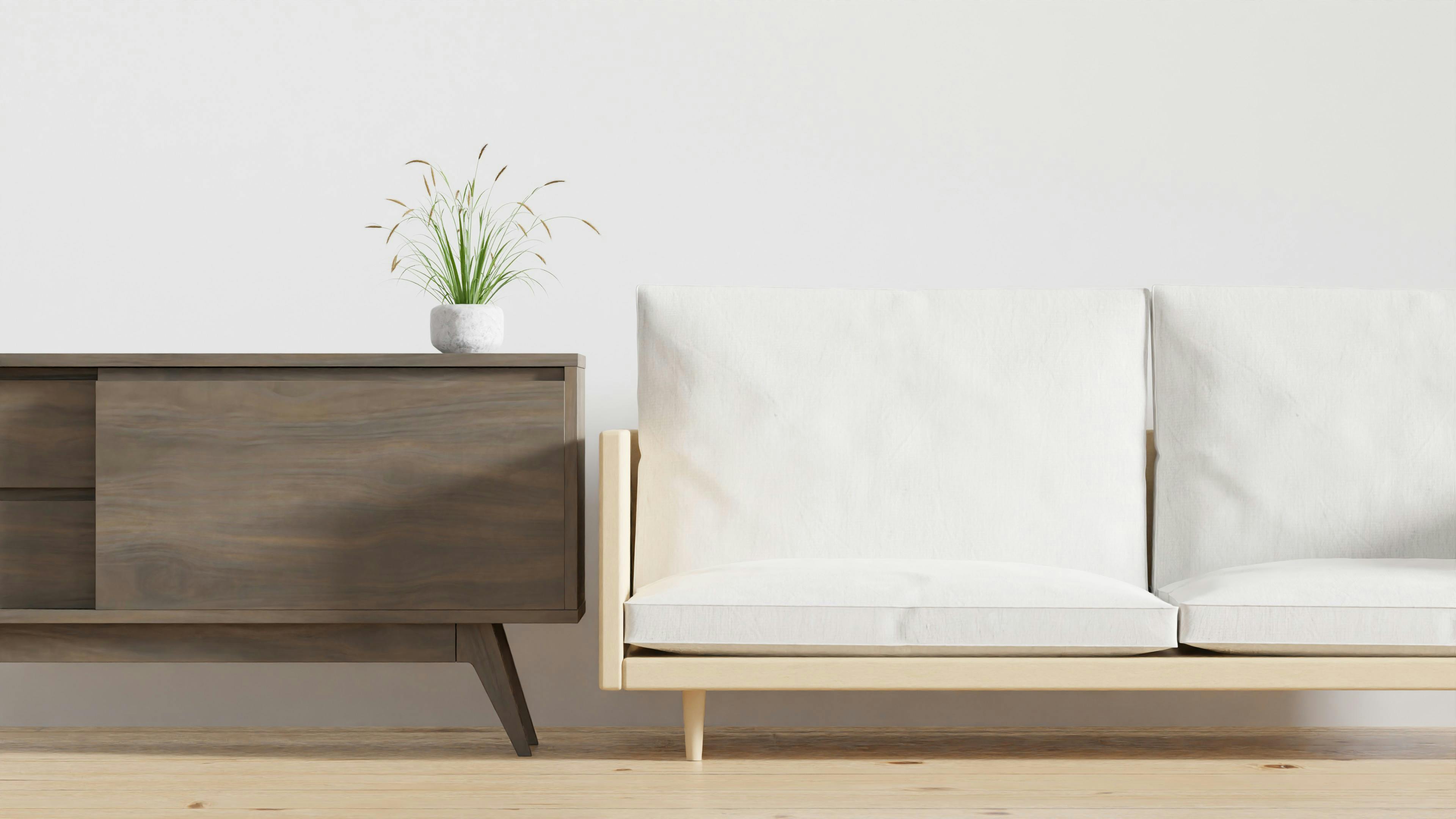 Bezowy tapczan w skandynawskim salonie z duzymi roslinami w donicach i stolikiem z ochronna taca