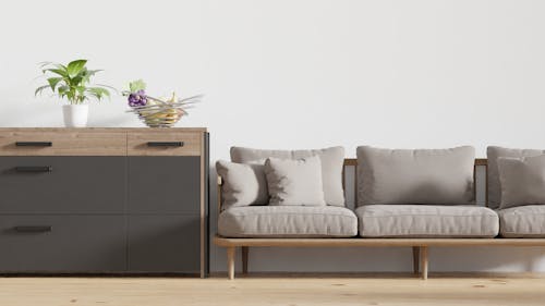 Beige Couch with Throw Pillows Beside a Wooden Chest of Drawers