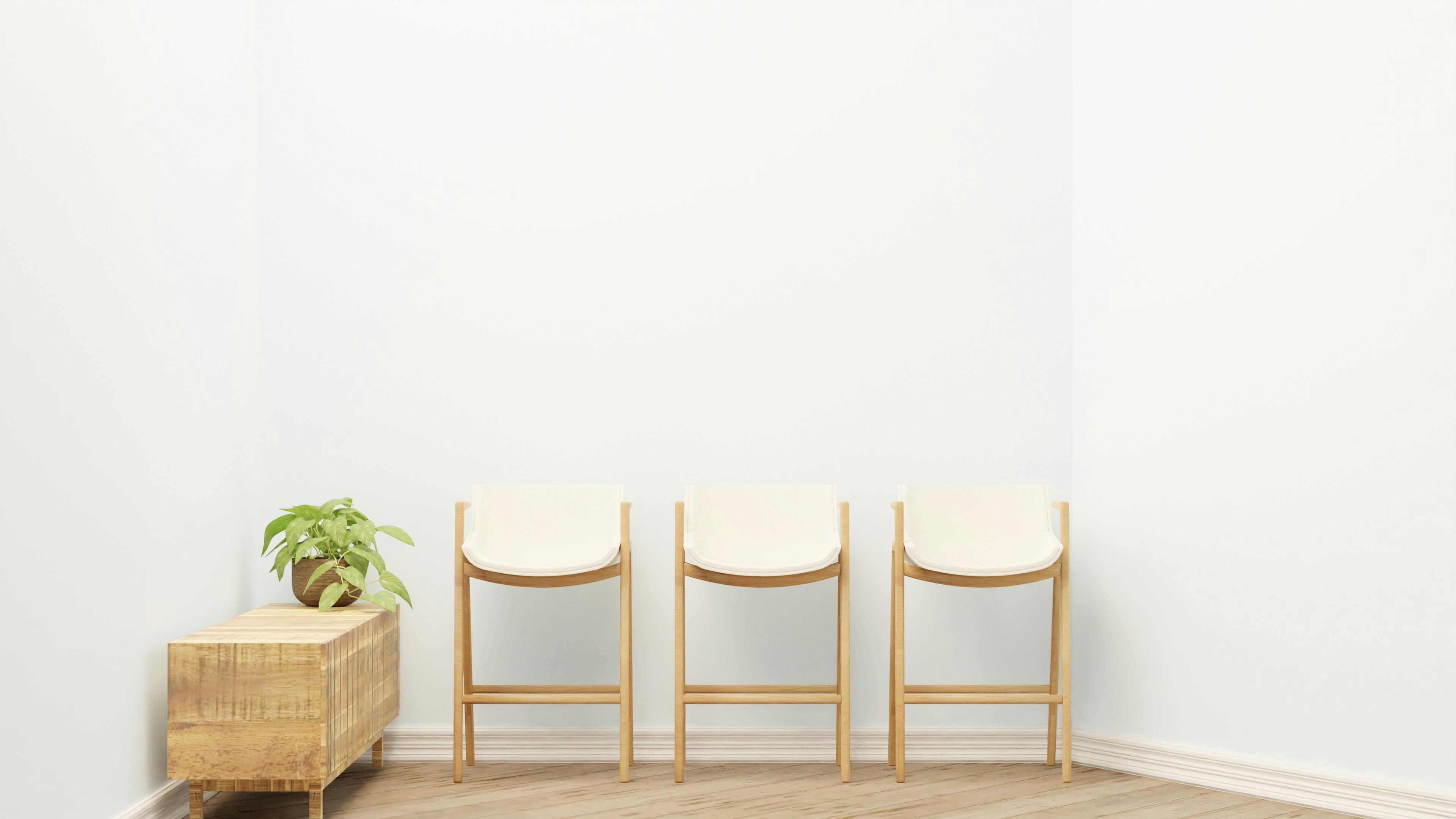 Free Simple minimalist design featuring wooden chairs and a potted plant in a spacious corner. Stock Photo