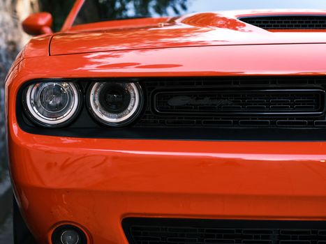 A detailed and vibrant close-up of a red Dodge Challenger's front grille and headlights, showcasing automotive design.