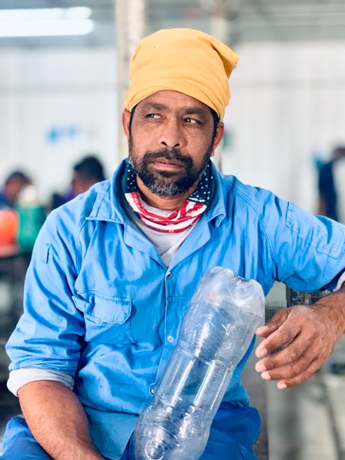 A Man Wearing Headscarf Holding Plastic Bottle while Looking Afar