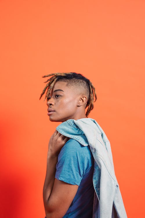 A Person in Blue Shirt Holding Denim Jacket while Looking Afar