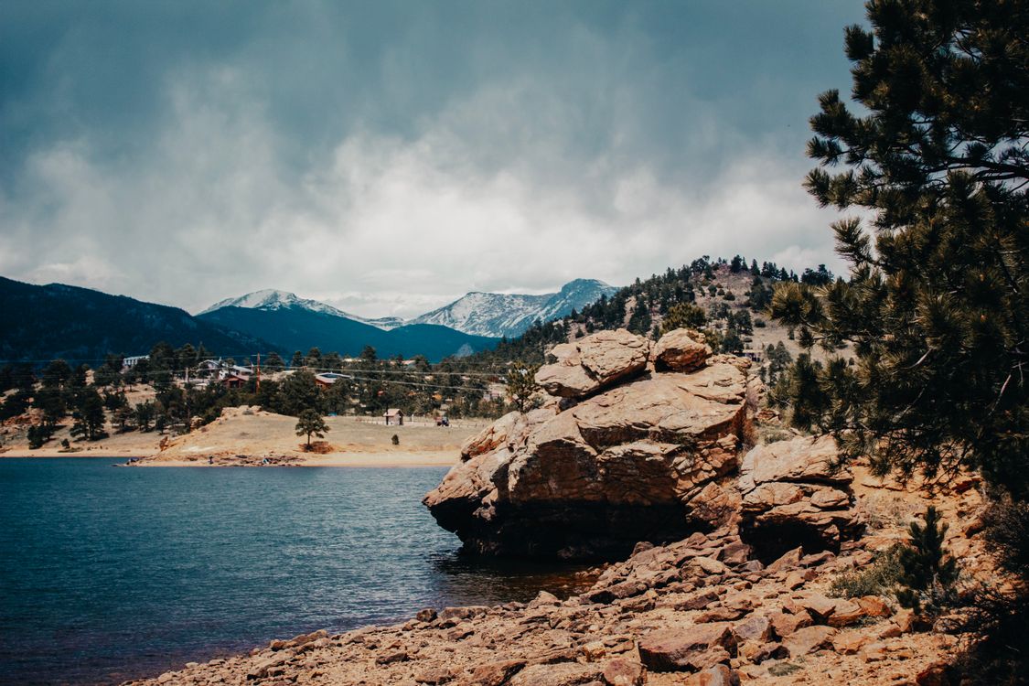Lake View With Rocks Big Rock on the Side of the Lake Under Cloudy Sky · Free Stock Photo