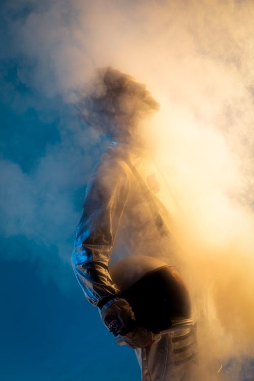 Free Man in Coverall Holding Helmet in Mist Stock Photo