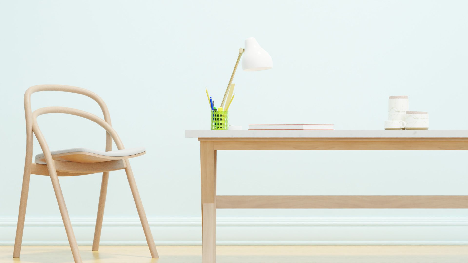 A minimalist office space featuring a wooden chair and desk, with a white lampshade and stationery.