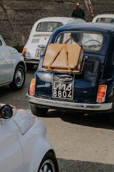 Classic vintage cars on the road, each with luggage attached, reflecting retro travel style.