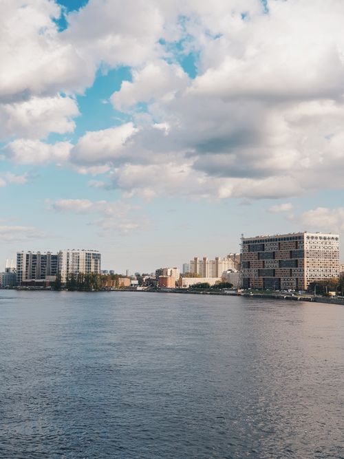 Free Peaceful cityscape along the river with modern architecture under a cloudy sky. Stock Photo