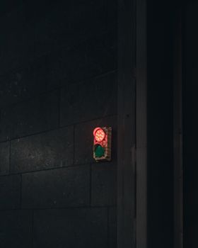 Red traffic light on a dark wall in Toronto at night, evoking an urban ambiance.